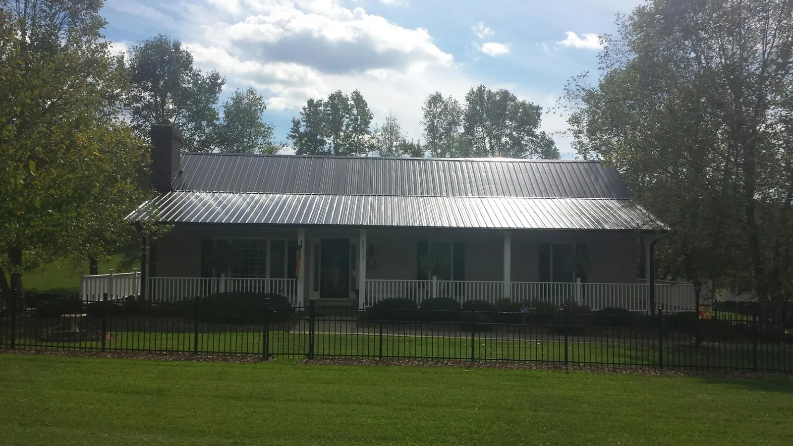 Gray metal roof on a brick ranch with a full width front porch — Gutter Guard Installation work by our crew in West Jefferson