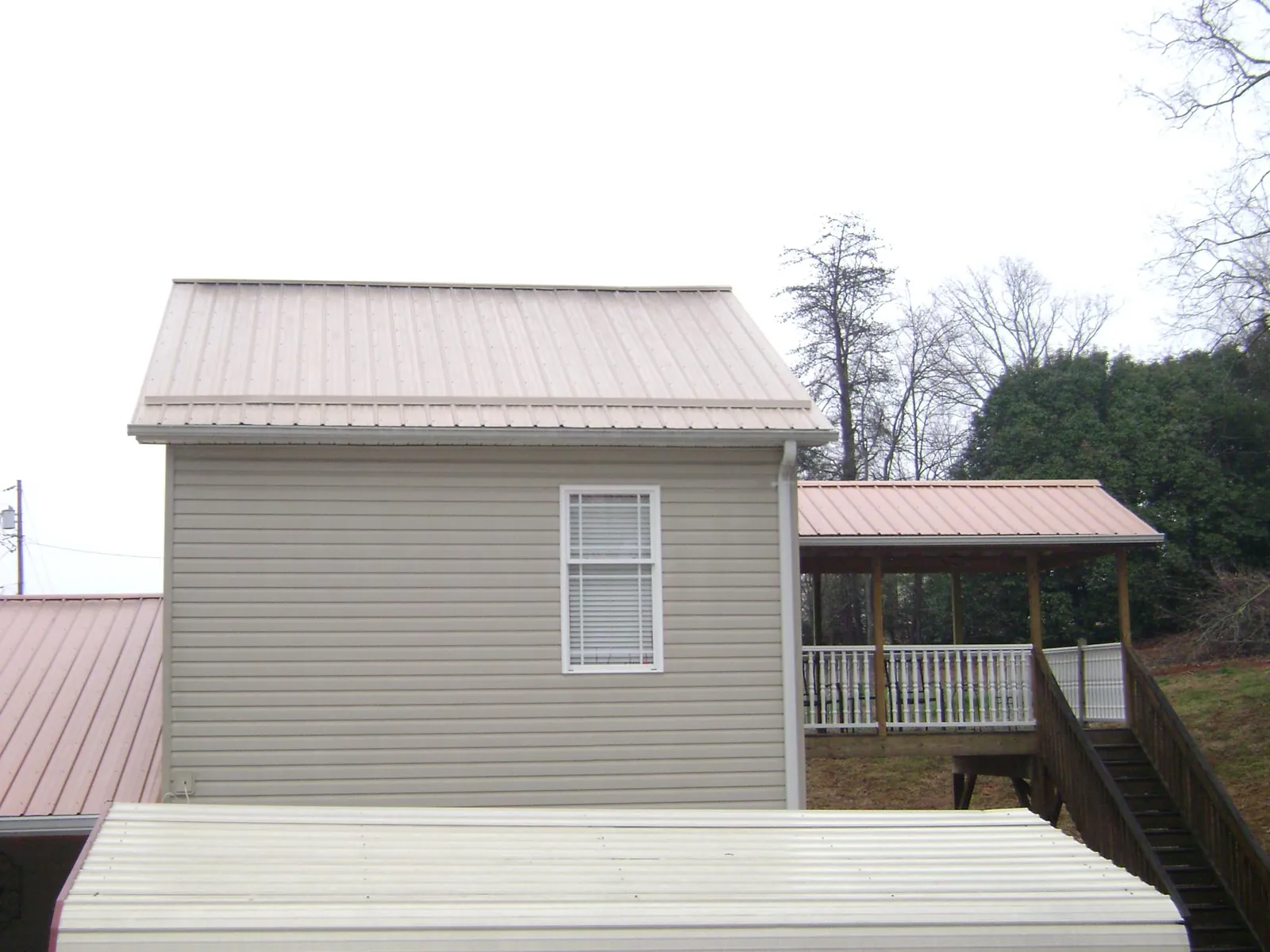 Tan metal roofs on a two story addition and attached porch, from a Roof Replacement job in West Jefferson