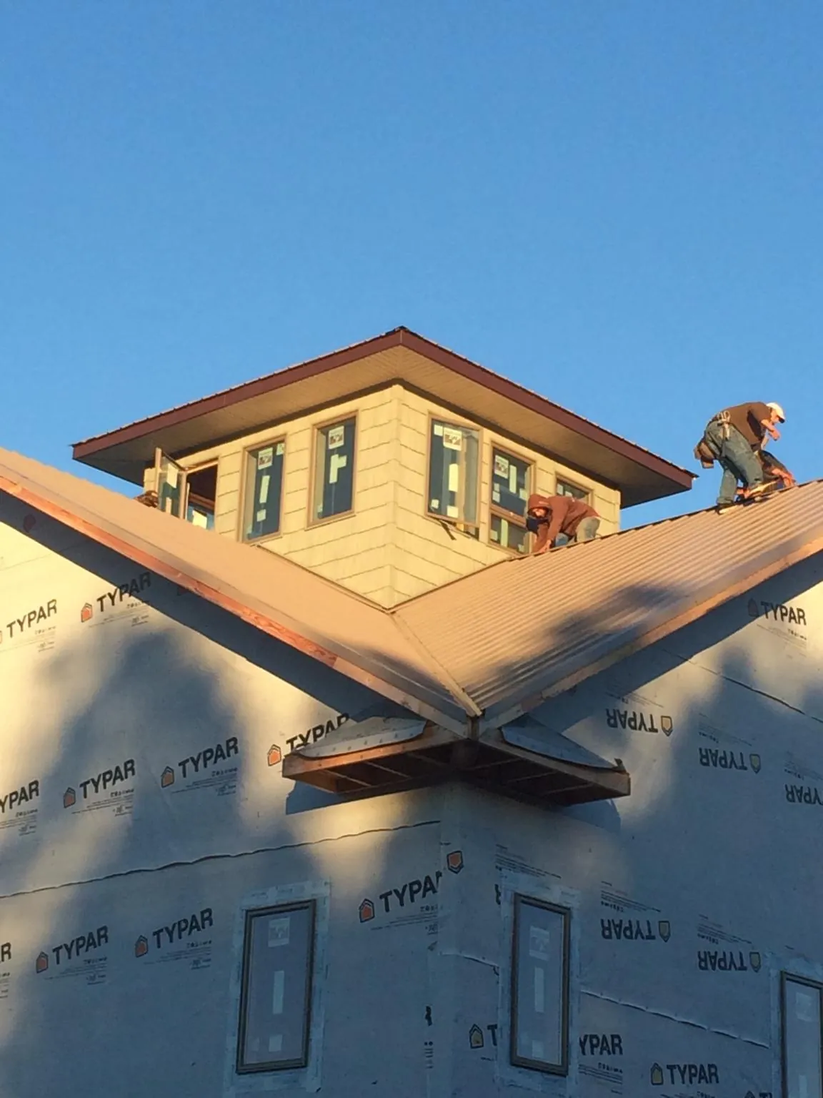 Roofers working around a rooftop cupola on a new metal roof at sunset — Roof Waterproofing in West Jefferson by Roofing Brothers